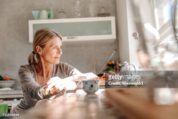 woman at home in kitchen looking out of window - wife of mario cuomo stockfoto's en -beelden