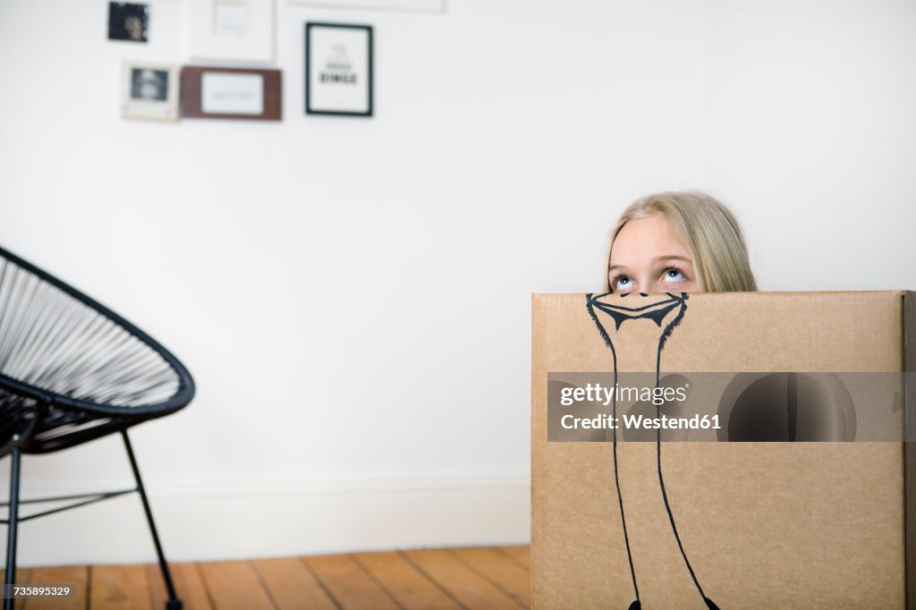 Girl inside a cardboard box painted with an ostrich