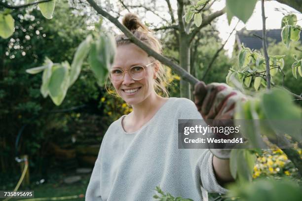 portrait of young woman holding branch of her quince tree - people portraits hobbies stockfoto's en -beelden