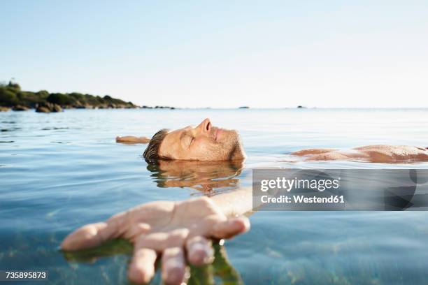 relaxed mature man floating in the sea - bathe in the sun stock pictures, royalty-free photos & images