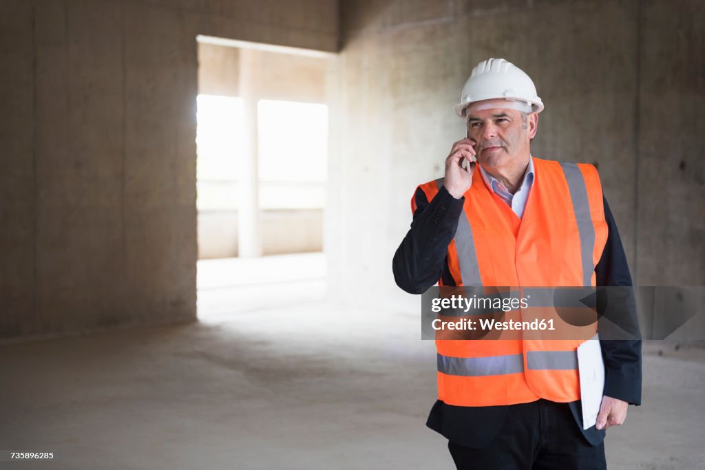Man on the phone wearing safety vest in building under construction