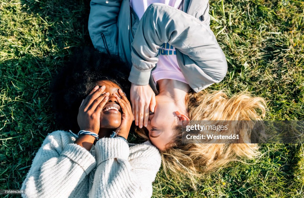 Two best friends telling secrets lying in the grass