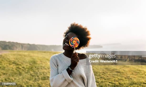 young woman having covering eye with a lollipop, laughing - lolly stockfoto's en -beelden