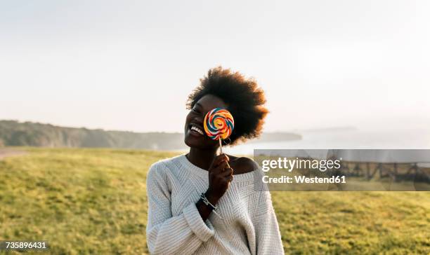 young woman having covering eye with a lollipop, laughing - lollipop stock pictures, royalty-free photos & images