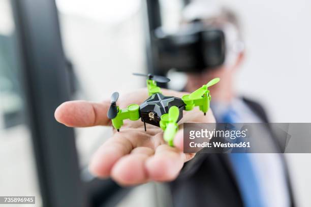 Mature businessman looking at drone through VR goggles