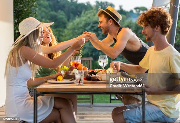 happy friends having dinner at outdoor table - summer cocktails garden party drinks stockfoto's en -beelden