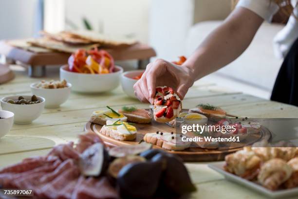 hand reaching for appetizers on table - servierplatte stock-fotos und bilder