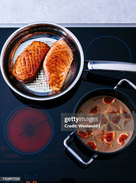 fried duck breast and pot of fig sauce on cook top - electric stove burner ストックフォトと画像