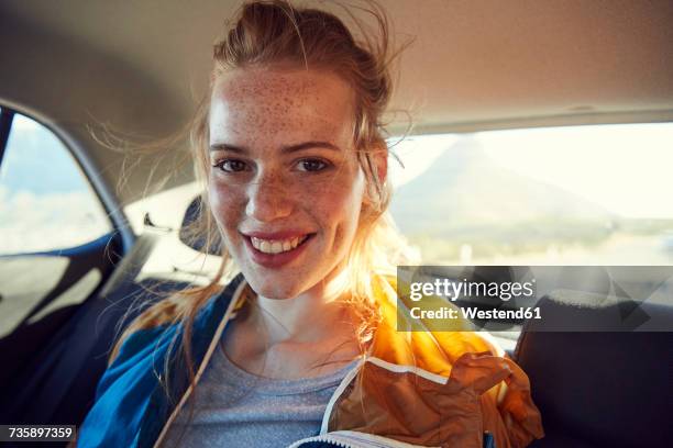 smiling young woman on the back seat of a car - freckle foto e immagini stock