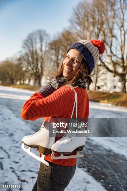 happy woman on canal carrying ice skates - bobble hat stock pictures, royalty-free photos & images
