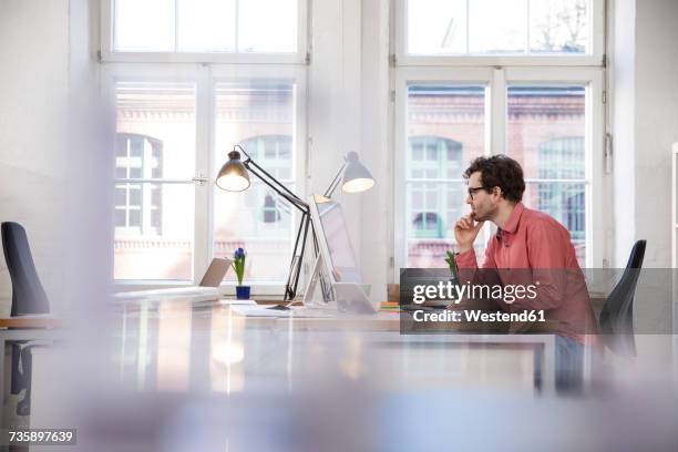 man sitting at desk in office - desk lamp fotografías e imágenes de stock