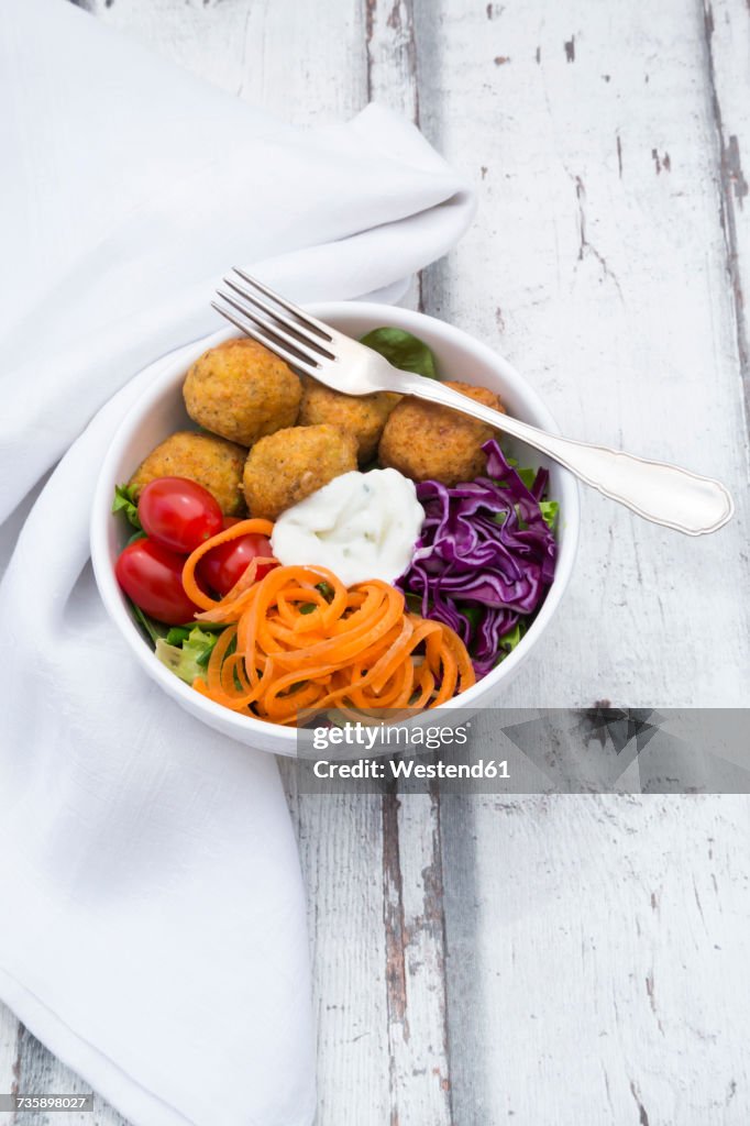 Lunch bowl of leaf salad, red cabbage, tomatoes, carrots, Falafel and yoghurt sauce