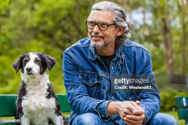 portrait of man with grey hair and beard sitting beside his dog on a bench - ethnicity stock pictures, royalty-free photos & images
