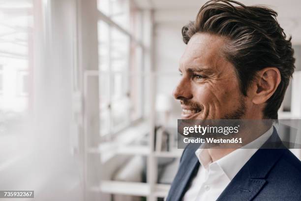 smiling businessman at the window - mann portrait seitlich stock-fotos und bilder