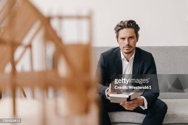 man with notebook on couch with architectural model in foreground - male man portrait one person business confident background stock pictures, royalty-free photos & images