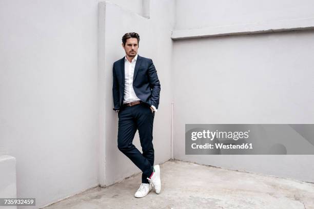 portrait of confident businessman leaning against a wall - luta fysisk ställning bildbanksfoton och bilder