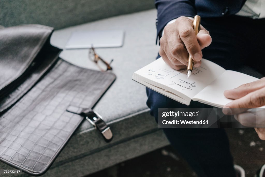 Close-up of businessman writing and drawing in notebook