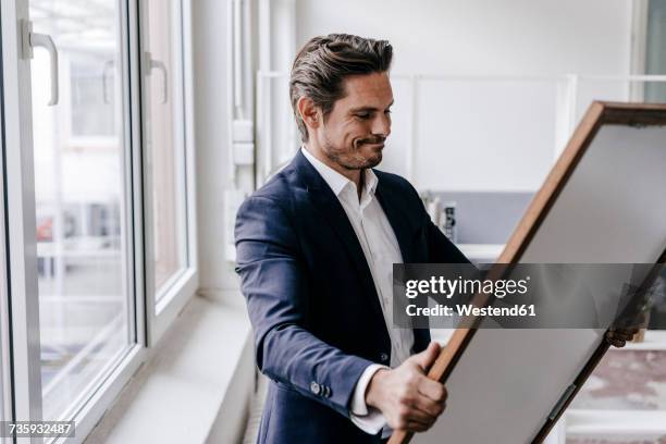 businessman holding picture frame - kunsthändler stock-fotos und bilder