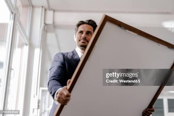 smiling businessman holding picture frame - kunsthändler stock-fotos und bilder