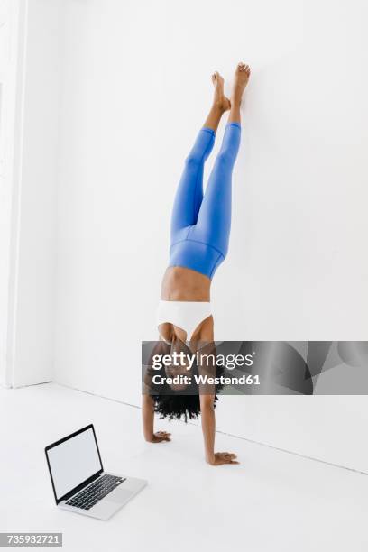 young woman practising yoga with laptop by her side - handstand stock pictures, royalty-free photos & images