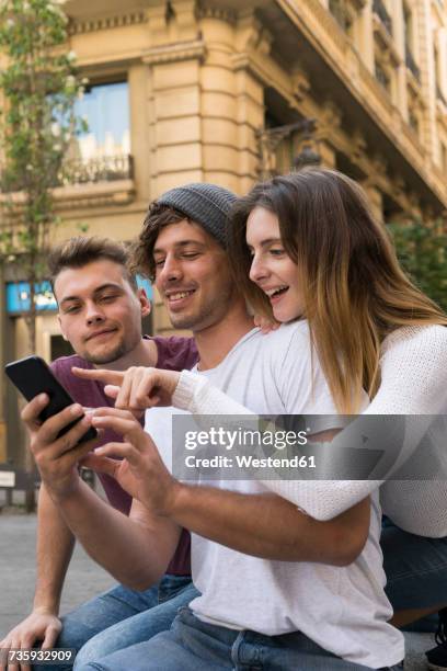 three friends using sharing cell phone in the city - indulgence fotografías e imágenes de stock