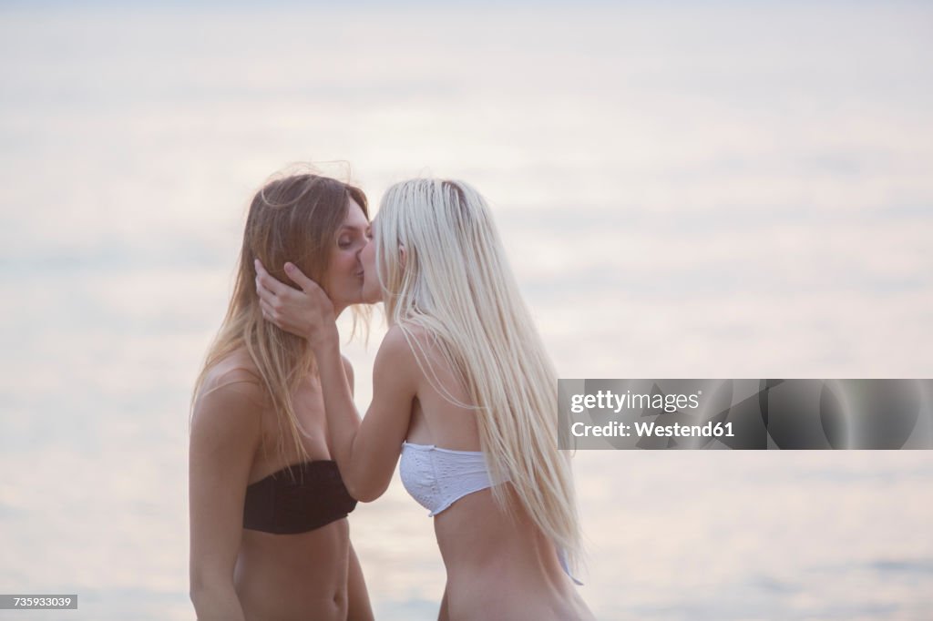 Two young women kissing at the sea