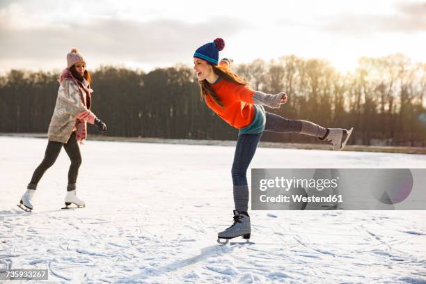 two women ice skating on frozen lake - eislaufen stock-fotos und bilder