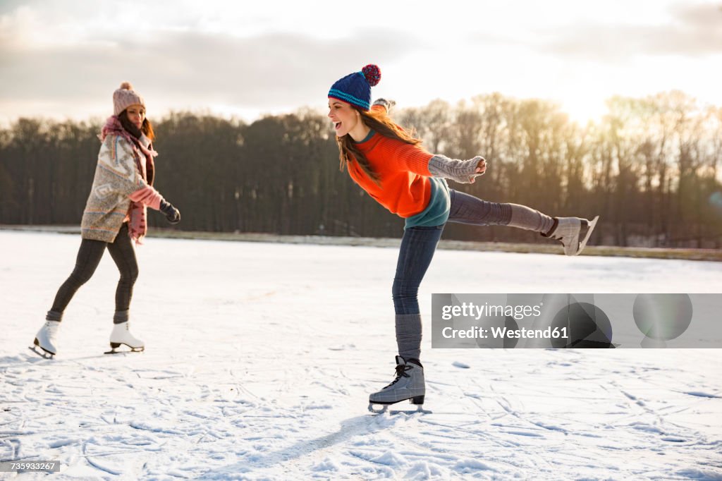 Two women ice skating on frozen lake