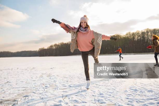 woman dancing with ice skates on frozen lake with friends - ice skate stock pictures, royalty-free photos & images