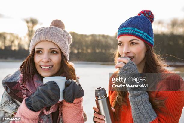 two women drinking hot beverages outdoors in winter - cologne winter stock pictures, royalty-free photos & images
