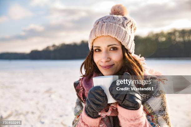 portrait of smiling woman drinking hot beverage from a cup outdoors in winter - mulled wine stock pictures, royalty-free photos & images