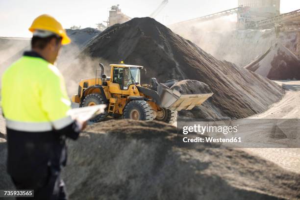 worker standing at quarry, using clipboard - open pit mine stock pictures, royalty-free photos & images