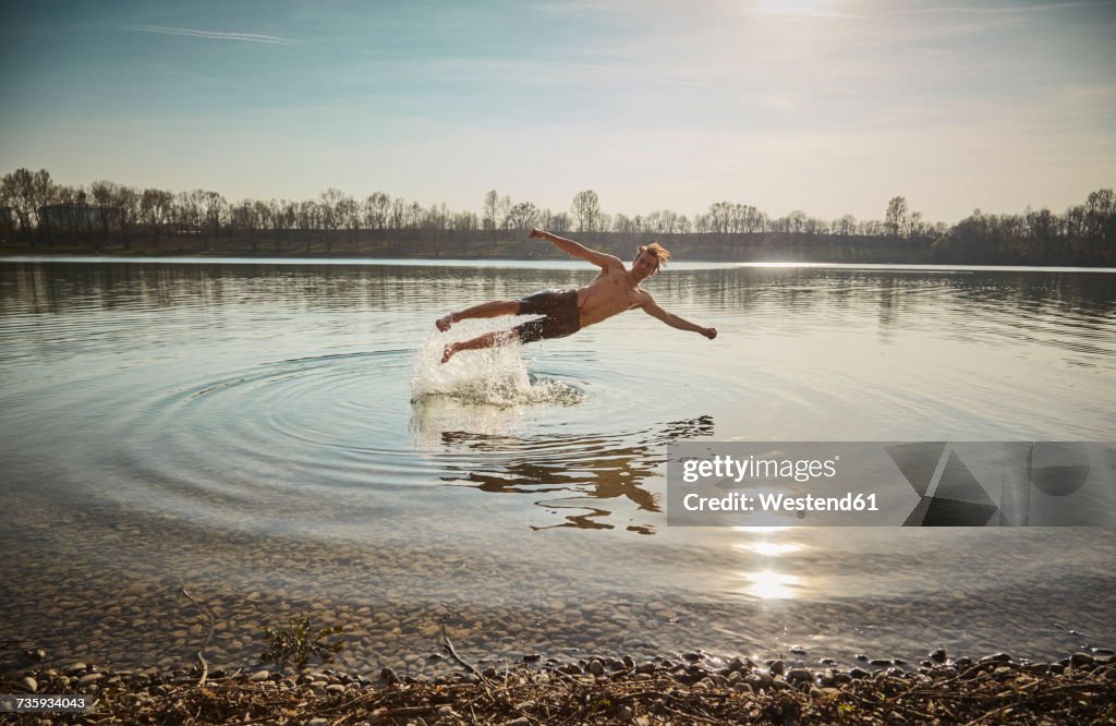 Germany, Bavaria, Feldkirchen, man jumping in lake