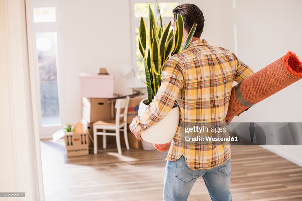 Young man carrying belongings in new home