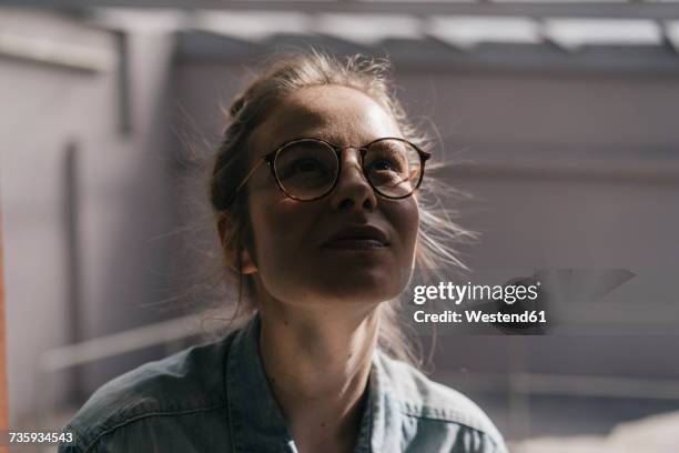 young woman with glasses looking up - optimismo stock-fotos und bilder
