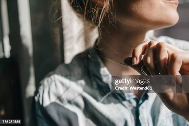 young woman holding pendant of her necklace - pendants foto e immagini stock