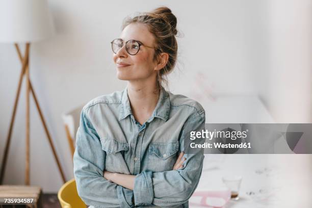 smiling young woman in office looking sideways - positive emotionen stock-fotos und bilder