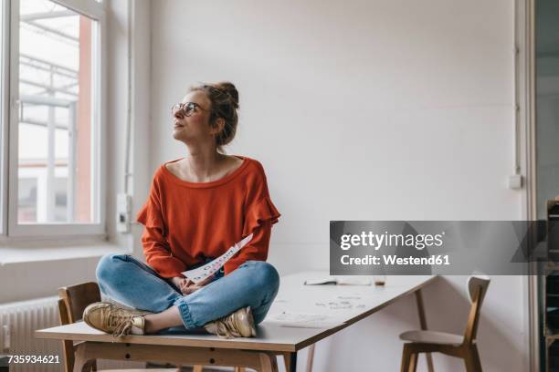 young woman sitting on table thinking - funky office stock pictures, royalty-free photos & images