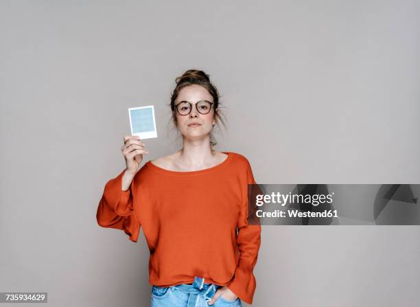 portrait of young woman holding instant photo - festhalten stock-fotos und bilder