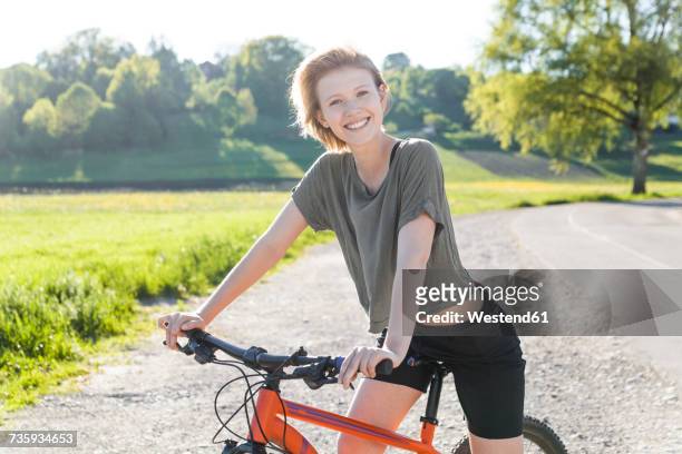 portrait of smiling young woman with mountain bike - fahrrad lenker stock-fotos und bilder