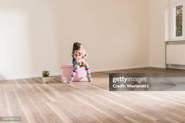 girl in empty apartment holding teddy - girl sitting on floor stock-fotos und bilder