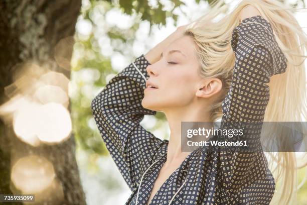 blond woman with eyes closed and hands in her hair in the morning - woman fresh air photos et images de collection