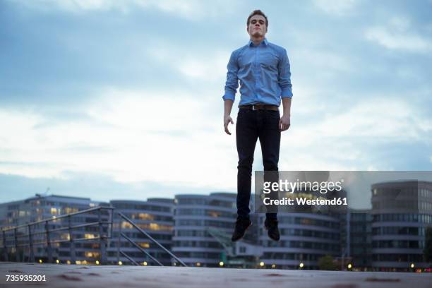 portrait of young man jumping in the air - hero corp stock pictures, royalty-free photos & images