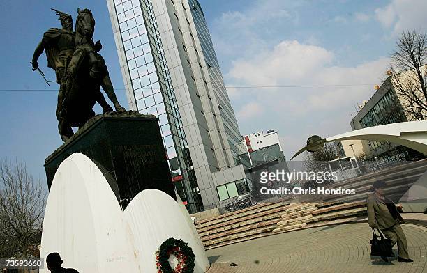 Woman walks downtown next to a statue of fifteenth century Albanian folk hero Skenderbeu and a modern office building March 15, 2007 in Pristina,...