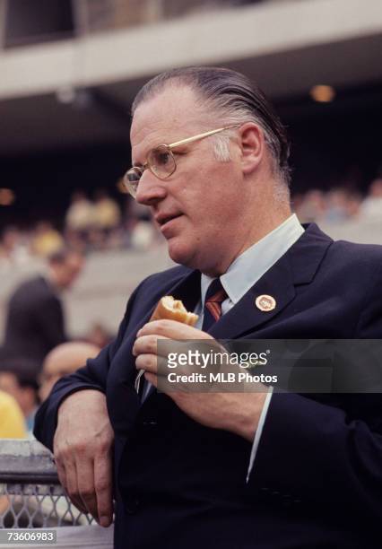 Major League Baseball Commissioner Bowie Kuhn eats a hot dog at a baseball game.