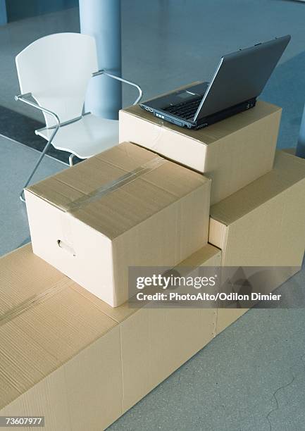 open laptop on stack of cardboard boxes, and empty chair - makeshift photos et images de collection