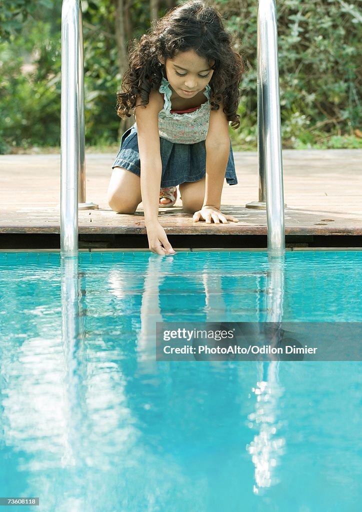 Pool Crounching Girl Crouching By Edge Of Pool Touching Surface Of Water High-Res Stock ...
