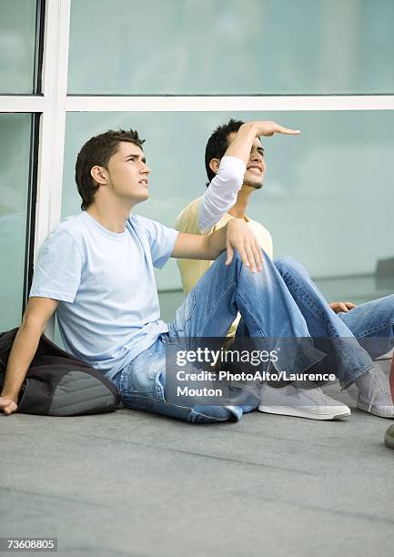 teen males sitting on ground, looking up - three quarter front view stock pictures, royalty-free photos & images