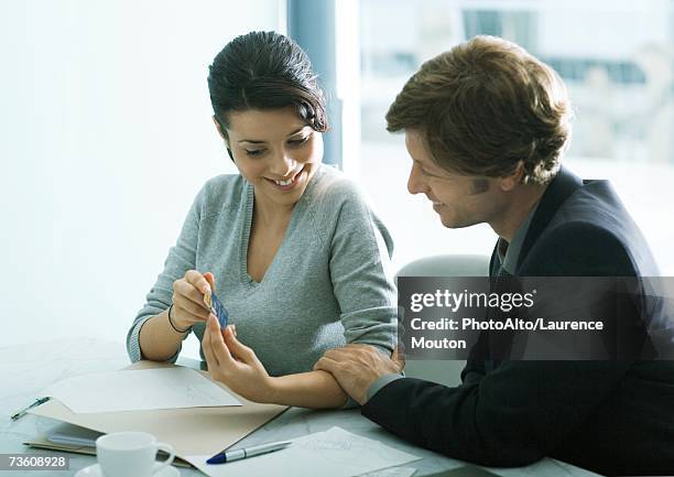 young woman showing man in suit credit card, man touching woman's arm - 辦公室戀情 個照片及圖片檔