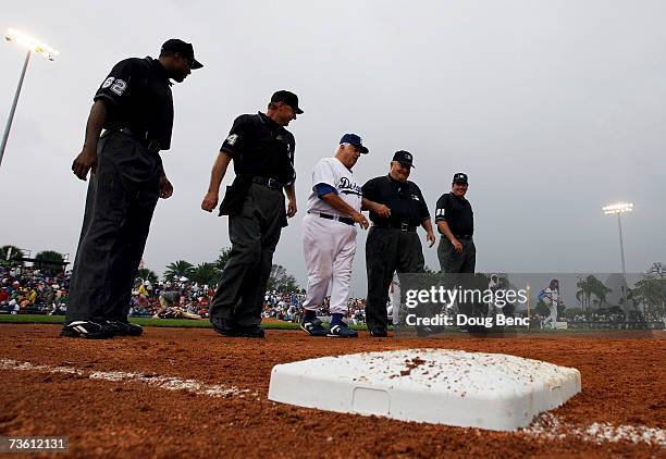 Tommy Lasorda of the Los Angeles Dodgers makes his way off the field with the four umpires after the rain canceled the game against the Boston Red...